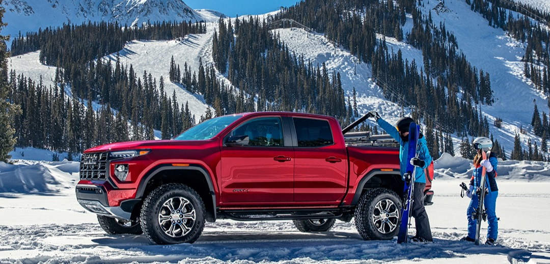 2025 gmc canyon in the snow with skiers loading up the truck bed