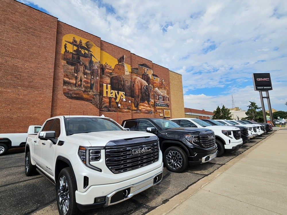 GMC trucks at Robert Brogden's Hays GMC parked in front of the Hays mural